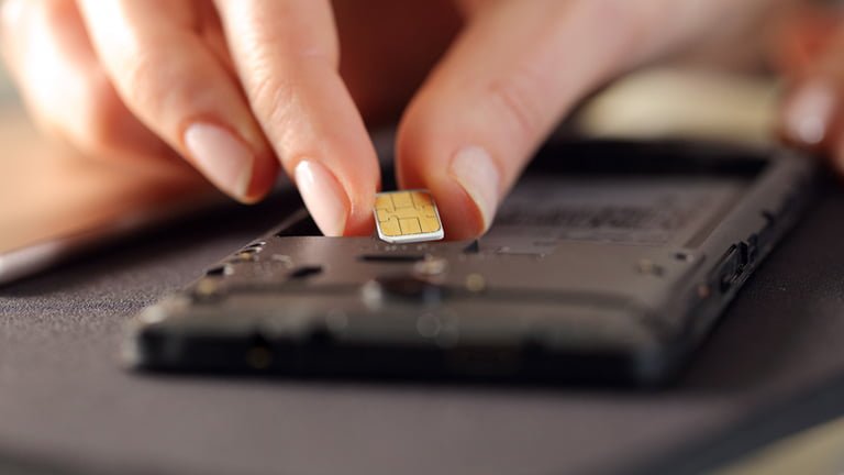 A hand is switching physical SIM cards for smartphones but eSIM doesn't require people to switch SIM cards physically