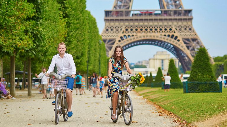 Europe-travel-hacks-helping-couple-traveler-riding-a-bike-happily-eiffel-tower